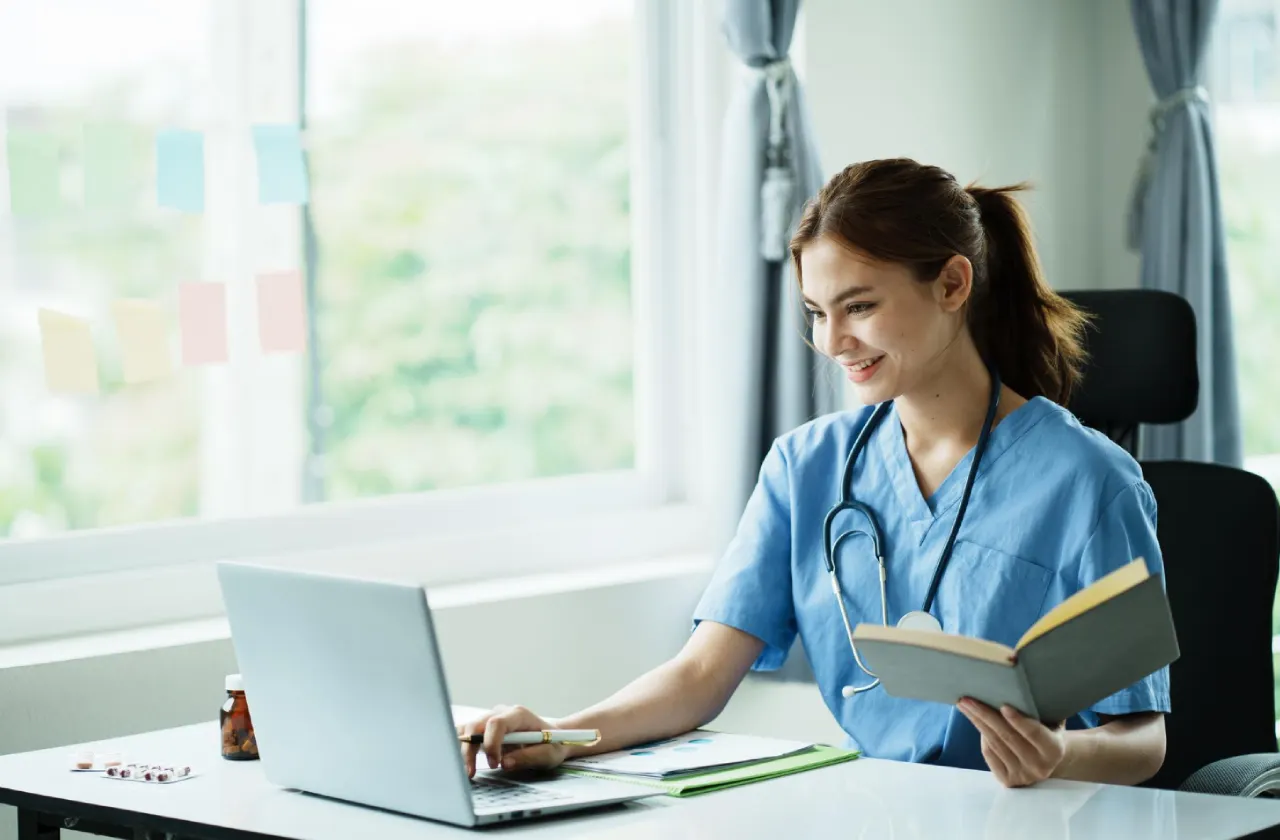 nurse-working-on-laptop-near-window