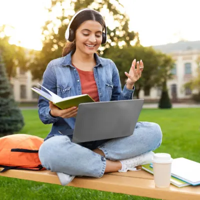 student-studying-outdoor-with-books-and-laptop